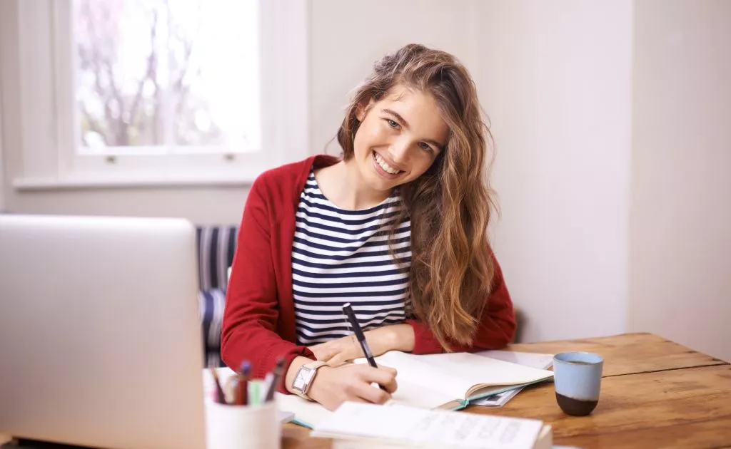studentessa sorridente con maglia a righe alla scivania con pc 
